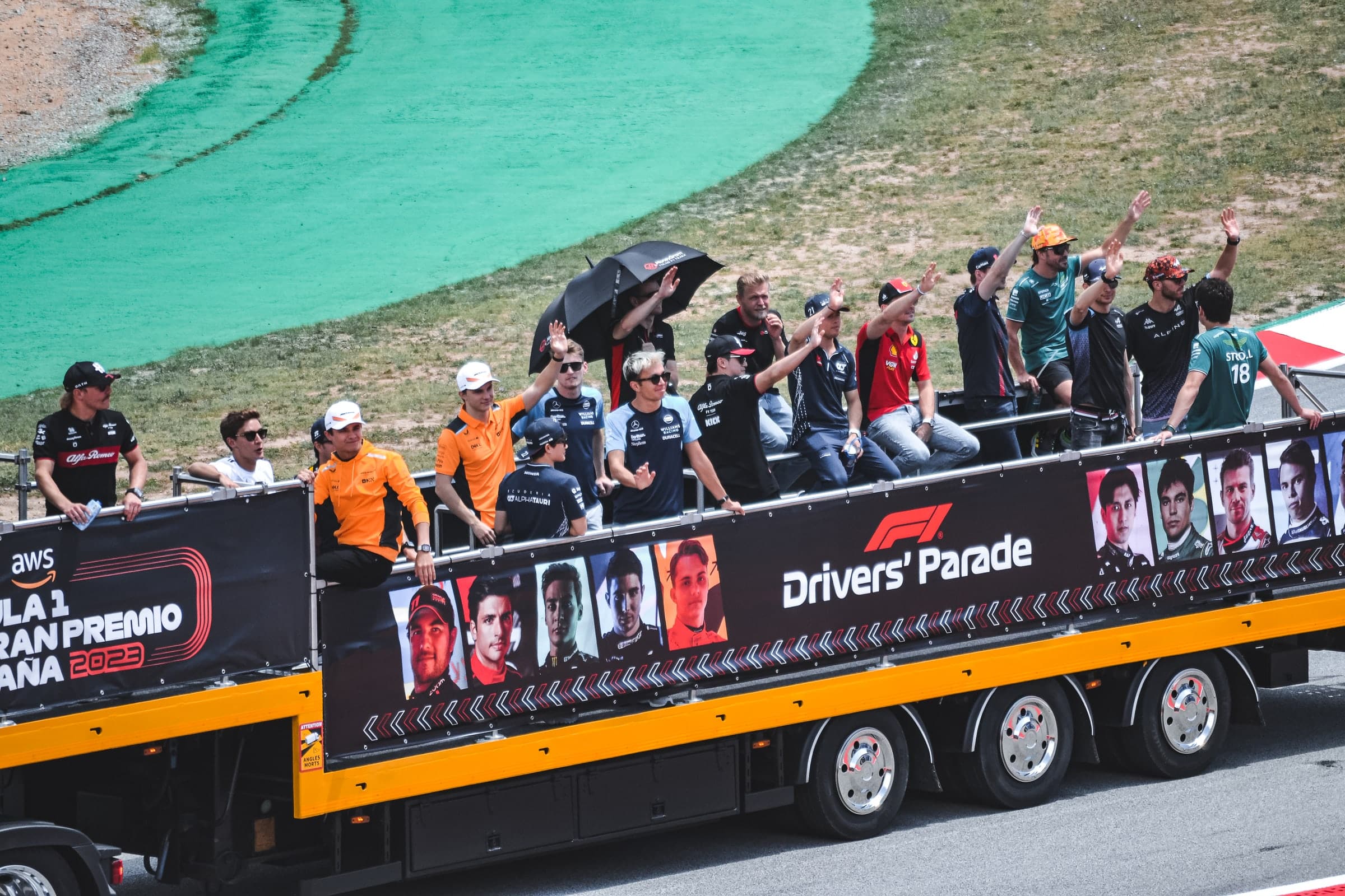 Formula 1 drivers wave to the crowd from the back of a truck during the drivers' parade at the 2023 Spanish Grand Prix.