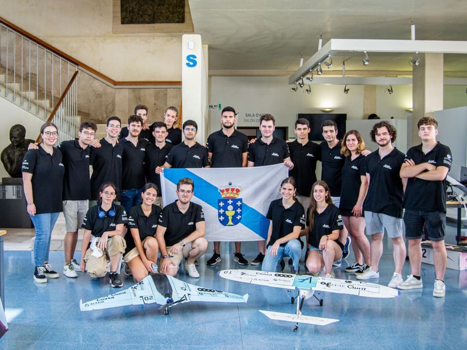 The UVigo Aerotech team, in black polo shirts and holding a Galician flag, stands behind its two aircraft, a flying wing and a conventional plane.