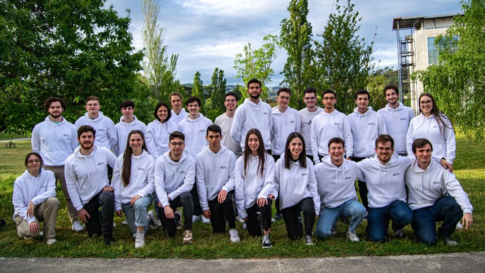 UVigo Aerotech group photo in 2023, around thirty people in white team hoodies on a campus lawn.